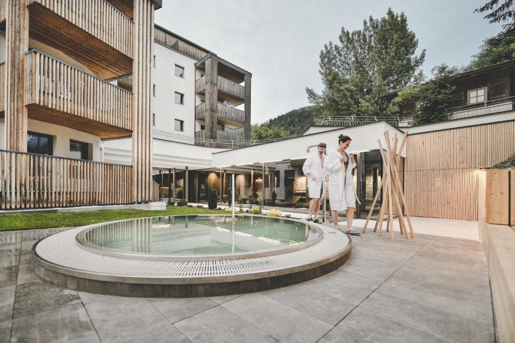 Dos mujeres con batas blancas al lado de una piscina en Arabella Retreat & Spa, en Nauders