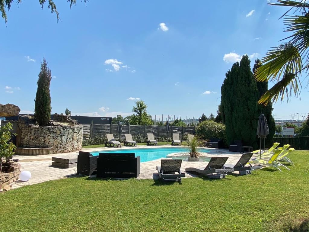 uma piscina com espreguiçadeiras e um monte de móveis em La Roselière em Saint-Quentin-Fallavier