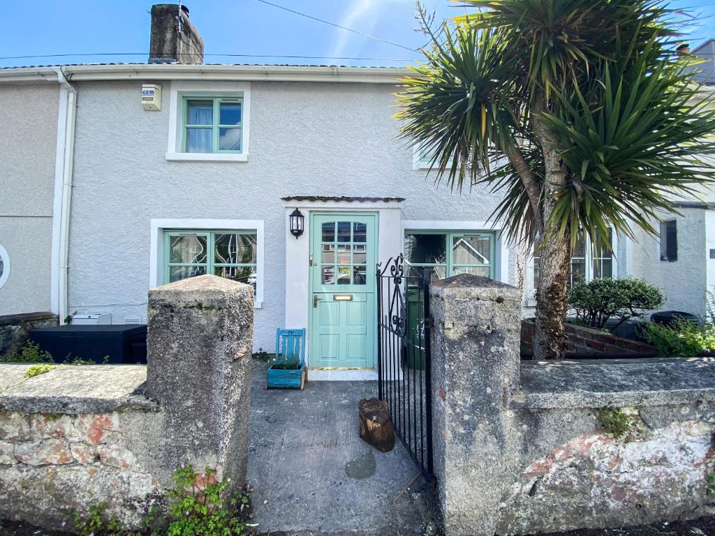 a house with a blue door and a palm tree at Inglenook Cottage near Porthcawl and Beaches in North Cornelly