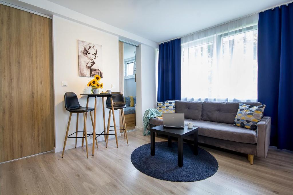 Una sala de estar con un sofá y una mesa con una computadora portátil. en Compact I - Faktura VAT, szybkie Wi-Fi, Netflix, niedaleko Centrum, en Koszalin