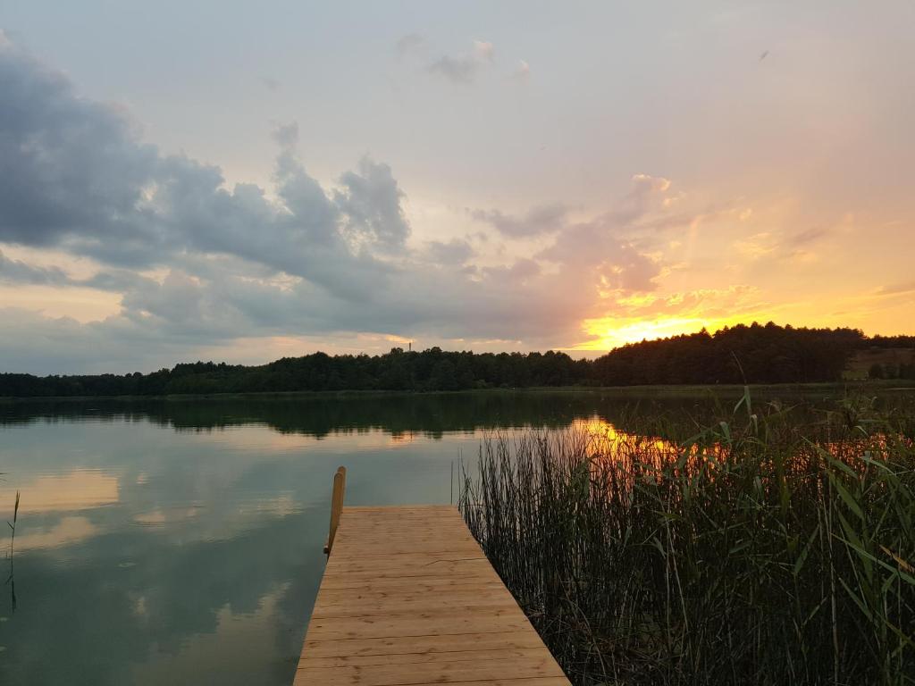 a dock on a lake with the sunset in the background at Nad Dąbrówką in Mała Huta