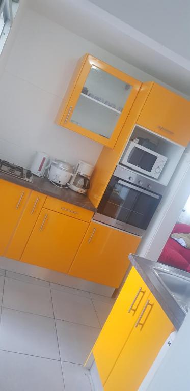 a small kitchen with yellow cabinets and appliances at La belle rose des îles in Les Abymes