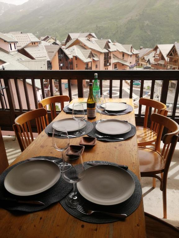 une table en bois avec des assiettes et des verres à vin sur un balcon dans l'établissement L'Ourson skis aux pieds, à Valmeinier