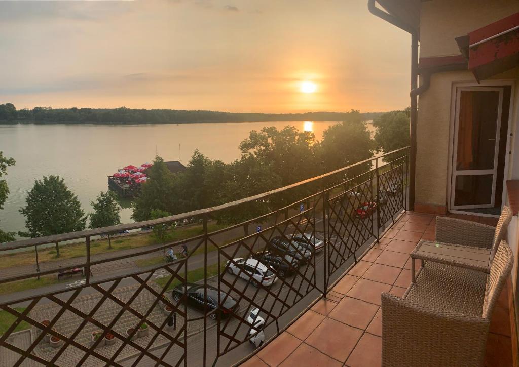 a balcony with a view of a lake at sunset at Apartamenty nad jeziorem in Ełk