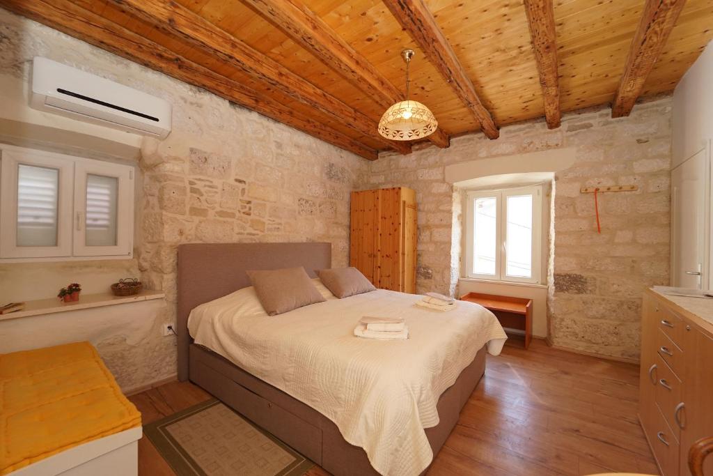 - une chambre avec un lit dans une pièce dotée de murs en pierre dans l'établissement Apartments Stelina, à Korčula