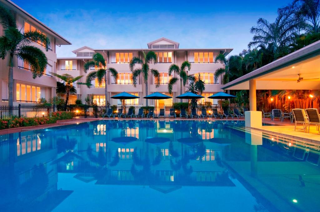 a hotel with a swimming pool in front of a building at Cayman Villas Port Douglas in Port Douglas