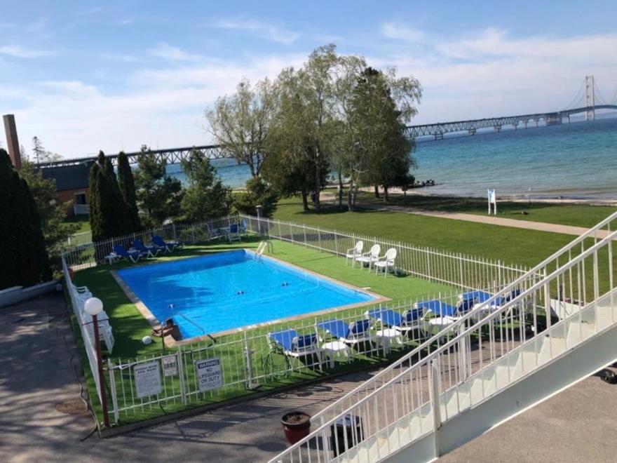 a swimming pool with a view of the ocean and a bridge at Riviera Motel in Mackinaw City