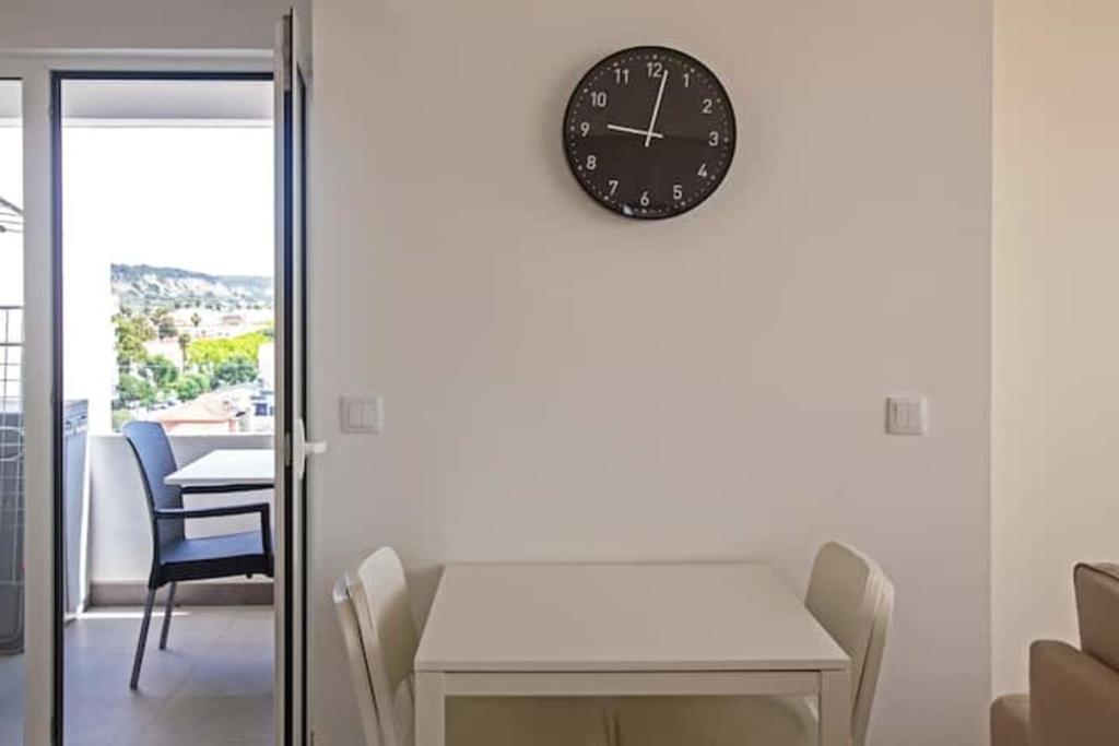 a clock on a wall with a table and chairs at Magnificent 1 Bedroom Apartment With Views Over The Ocean in Costa da Caparica
