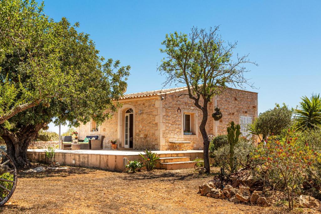 una casa de piedra con árboles y un patio en Finca Bassa Serra, en Santanyí