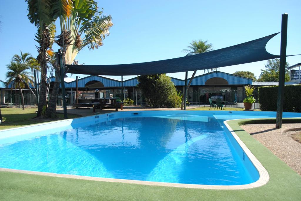 une grande piscine bleue avec un auvent au-dessus dans l'établissement David Motor Inn, à Rockhampton