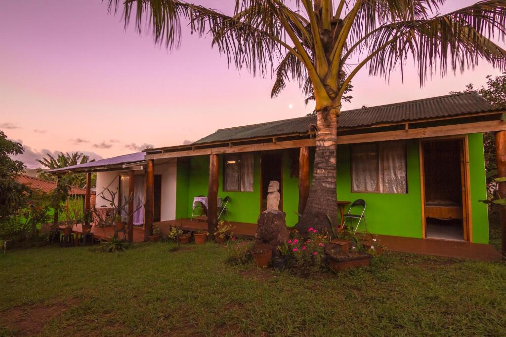 a green house with a palm tree in front of it at Cabañas Nua e Koro in Hanga Roa