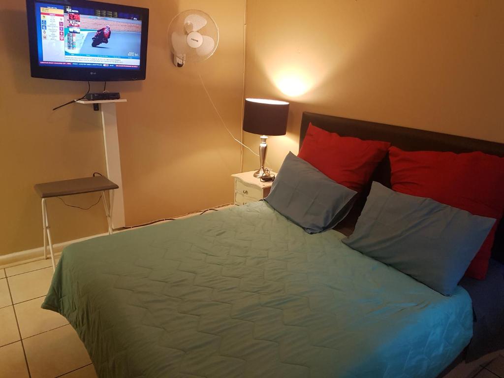 1 dormitorio con 1 cama y TV en la pared en The Fairlands Hideout en Johannesburgo