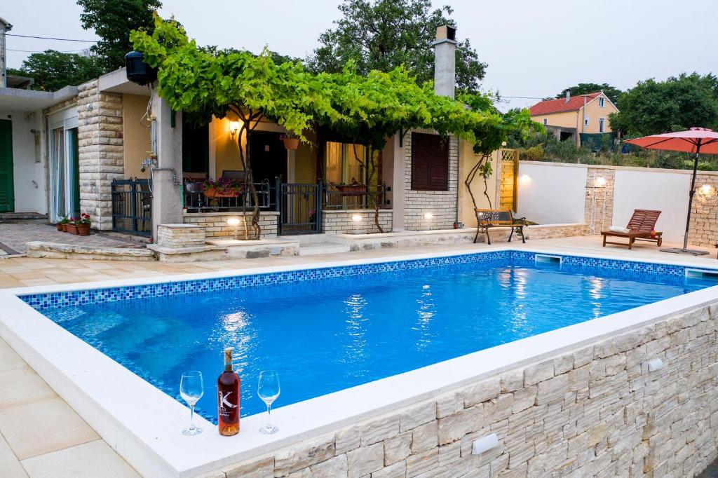 una piscina con una botella de vino frente a una casa en Country House Korlat en Benkovac