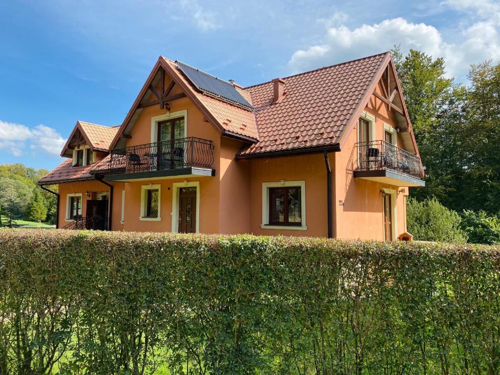uma casa com uma sebe à sua frente em Miodowa Polana em Polańczyk