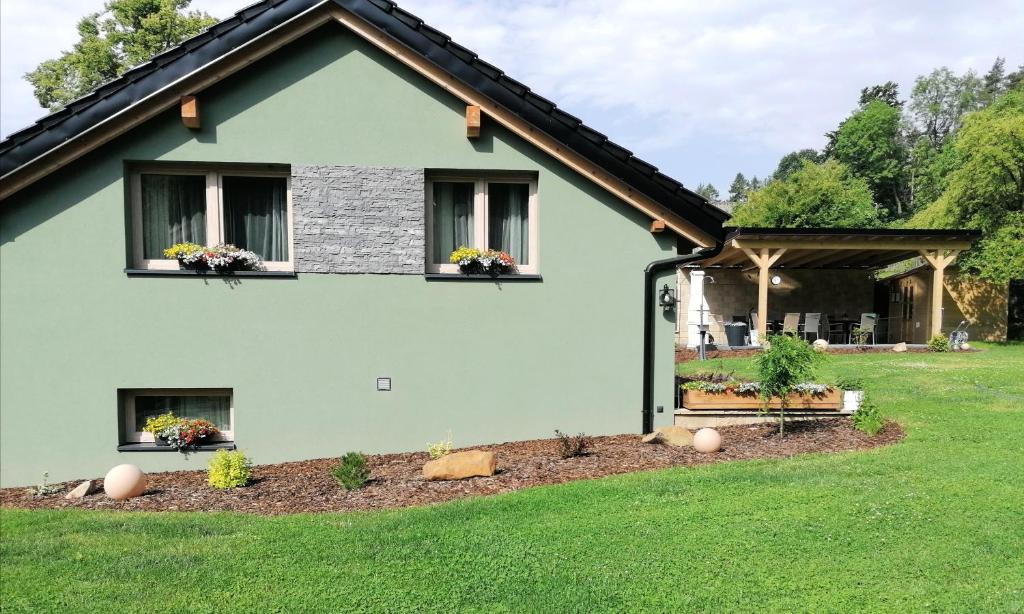 zielony dom z kwiatami w oknach w obiekcie Apartmány Okrouhlá w mieście Nový Bor