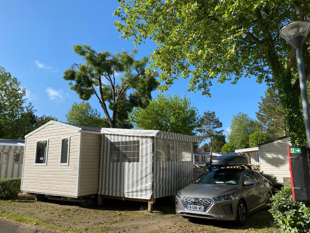 un coche aparcado delante de una casa pequeña en Le Sherwood - Mobil-Home, en Saint-Jean-de-Monts