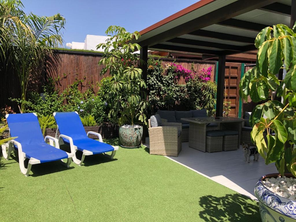 een patio met twee blauwe stoelen op het gras bij Bungalow Portos with amazing privet garden in Playa del Inglés