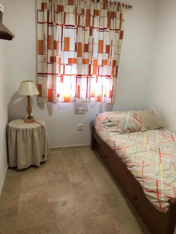 sypialnia z łóżkiem i stołem z lampką w obiekcie Apartamento en Conil cerca de Playa y Centro w mieście Conil de la Frontera