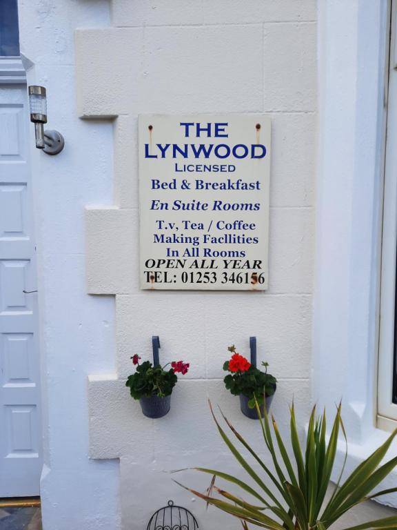 a sign on a white wall with two potted plants at Lynwood Hotel in Blackpool