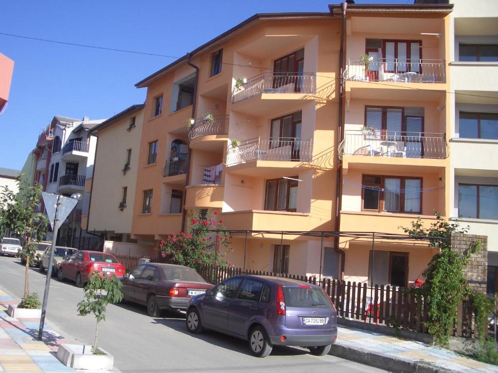 a building with cars parked in front of it at Primorski Briz Guest House in Primorsko