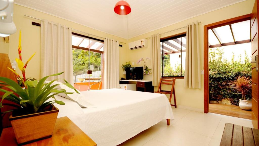 1 dormitorio con 1 cama blanca grande y ventanas en Pousada El Parador, en Búzios