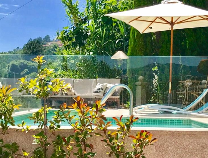 a swimming pool with an umbrella next to a swimming pool at Pedacinho de Mundo Douro in Passinhos de Cima