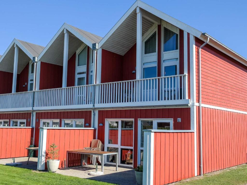 ein rotes Gebäude mit einem roten Zaun und einem Tisch in der Unterkunft Holiday home Løkken CXVI in Løkken
