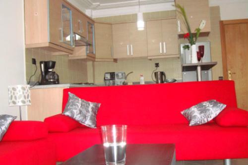 a red couch in a kitchen with a table at Appartement de luxe in Asilah