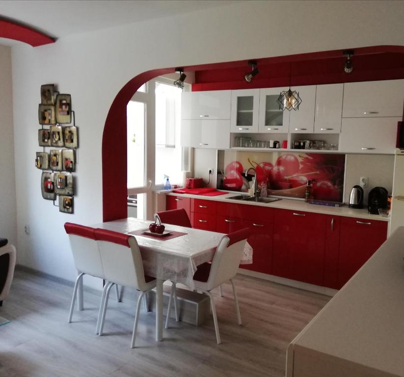 a kitchen with red cabinets and a white table and chairs at Apartment Ani in Veliko Tŭrnovo