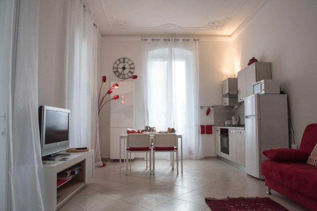 Una sala de estar con un televisor y una mesa con sillas. en Principe Apartment, en Génova