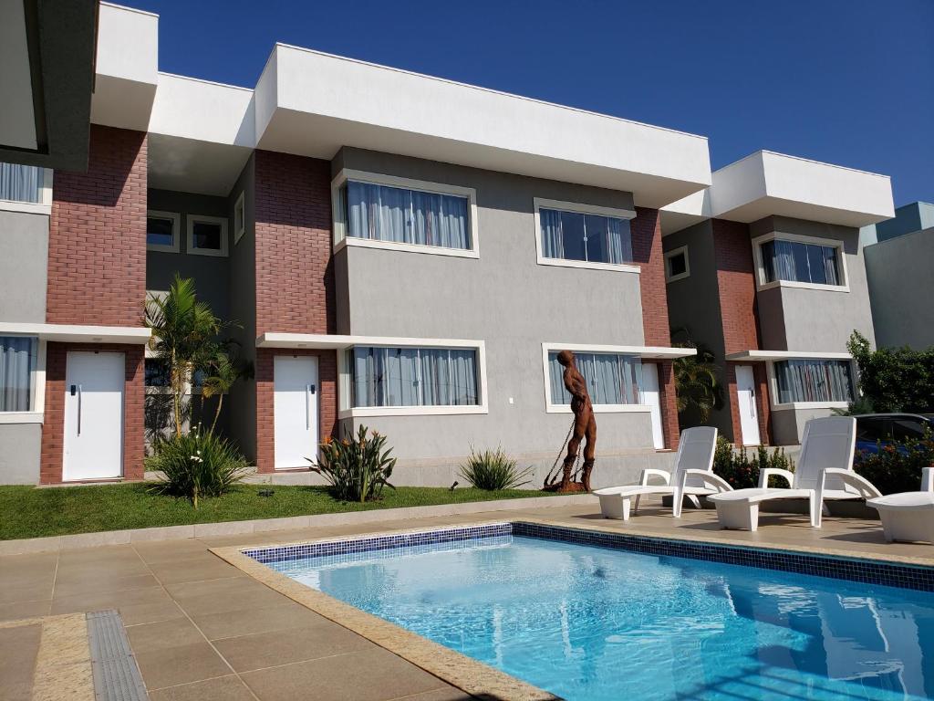 a building with a swimming pool in front of a house at VILLA CAPITÓLIO in Capitólio