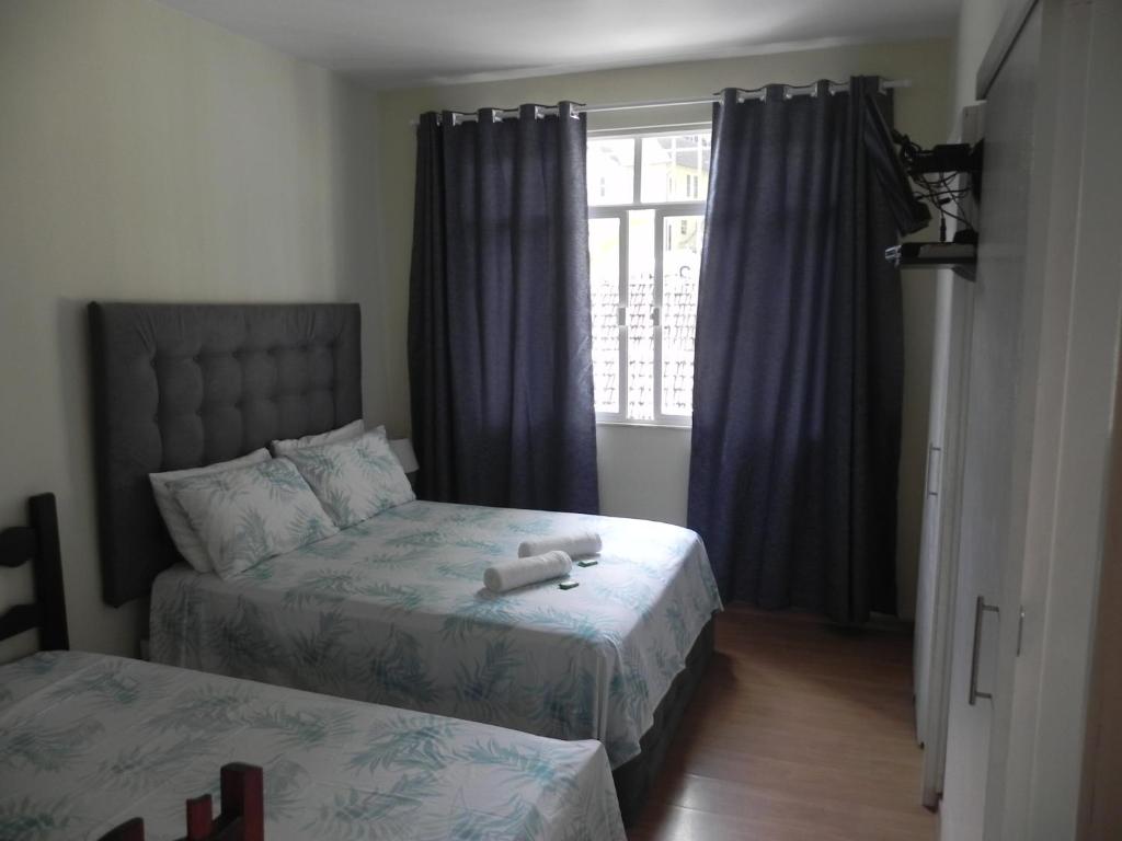 a bedroom with two beds and a window at Aconchego Valparaíso in Petrópolis
