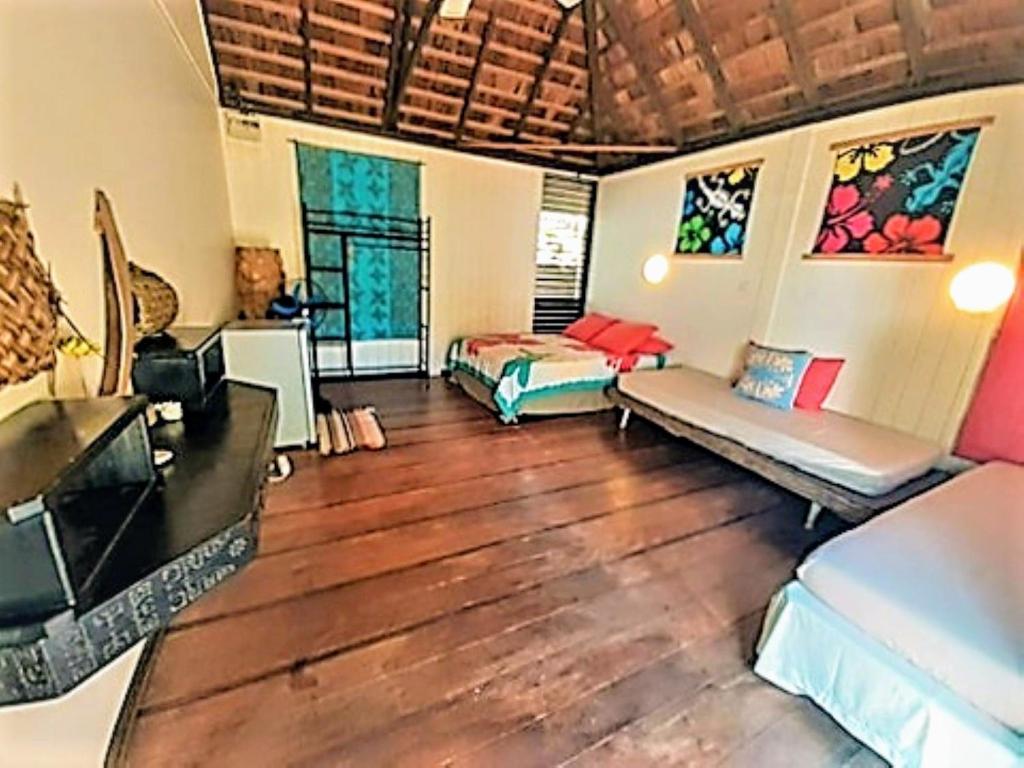 ein Wohnzimmer mit 2 Betten und Holzböden in der Unterkunft MOOREA - Local Spirit 6 in Hauru