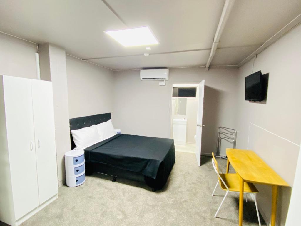 um quarto com uma cama e uma mesa em HIT Hostel em Auckland