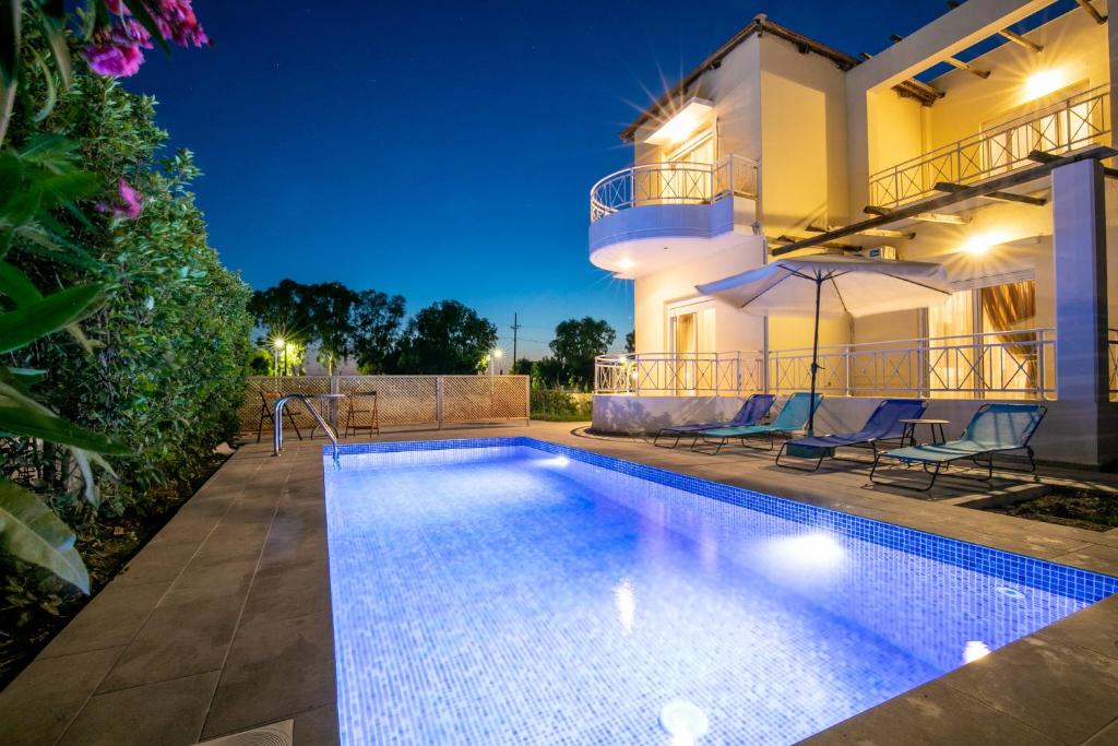 a swimming pool in front of a house at night at Rose Garden House in Kremasti