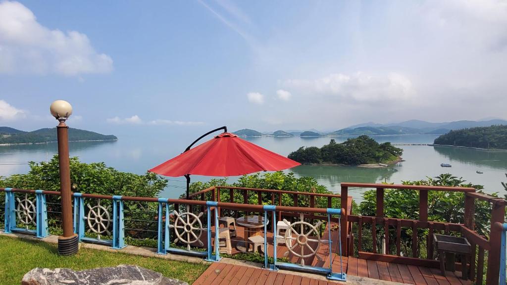 a patio with an umbrella and a view of a lake at Oh My Family Pension in Yeosu