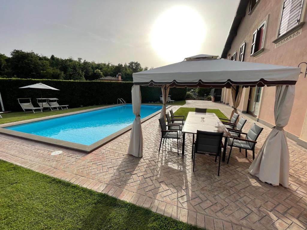 una mesa y sillas bajo una sombrilla junto a la piscina en Villa Gilda en Bracciano