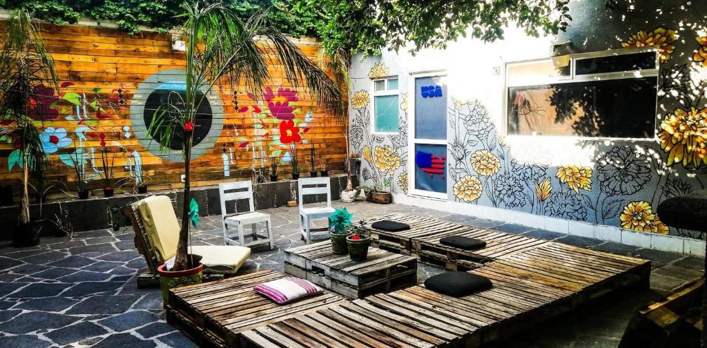 un patio con un banco de madera y una pared con un mural en Casa Internacional Querétaro en Querétaro