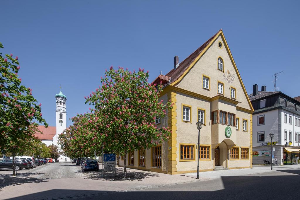 un bâtiment jaune dans une rue avec une tour d'horloge dans l'établissement JOESEPP´S HOTEL am Hallhof, à Memmingen