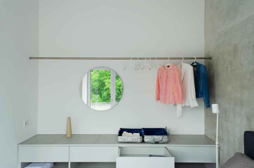 Habitación blanca con espejo y estante con ropa en seelandsuite Bodensee, en Bermatingen