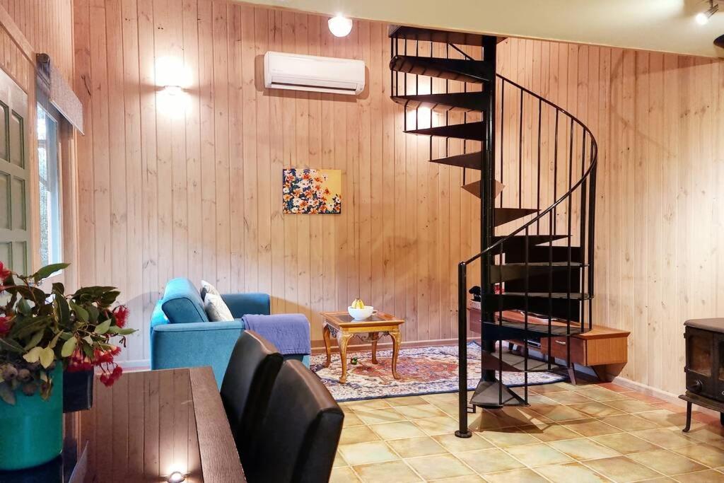 a living room with a blue couch and a spiral staircase at Native Garden Retreat in Gisborne