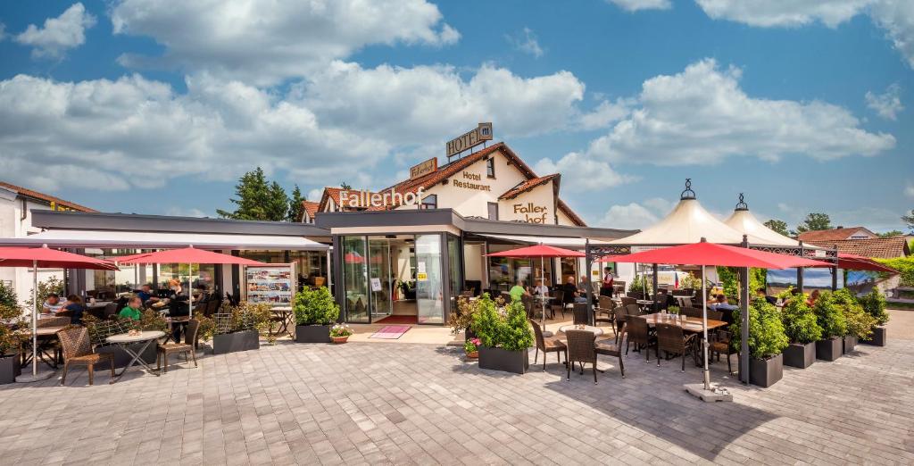 eine Außenterrasse mit Tischen, Stühlen und Sonnenschirmen in der Unterkunft Hotel Restaurant Fallerhof in Bad Krozingen