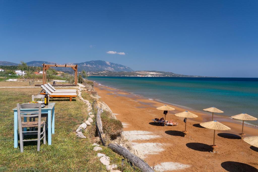 a beach with umbrellas and chairs and the ocean at Chloe Apartments in Lixouri