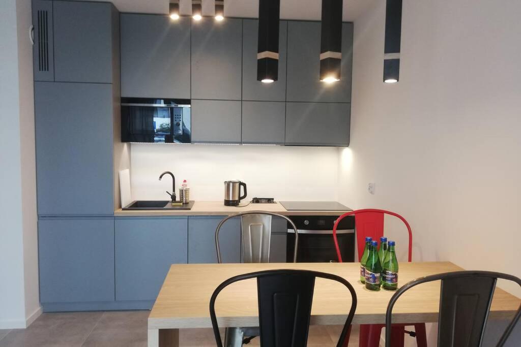 uma cozinha com armários azuis e uma mesa com cadeiras em Apartament na Rydlówce na Cracóvia
