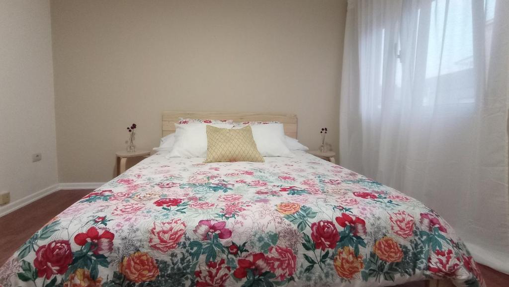 a bedroom with a bed with a floral bedspread at O Lagar apartamento grande y luminoso. 8 personas. in Pobra do Caramiñal