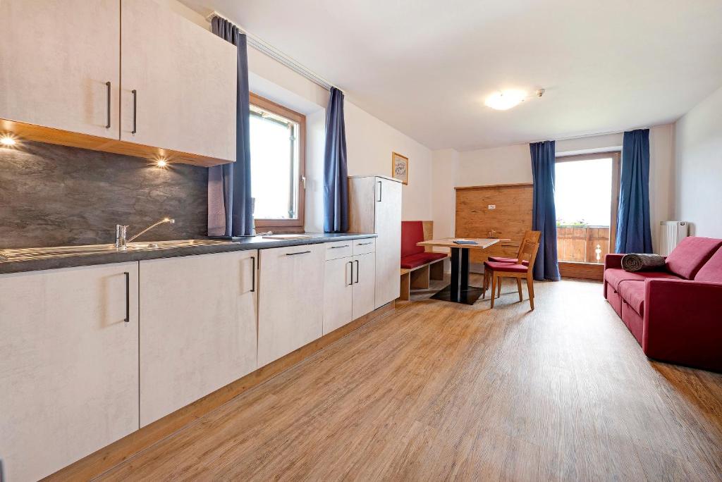 cocina y sala de estar con sofá rojo en Residence Condor Apt Eidechsspitz, en Maranza