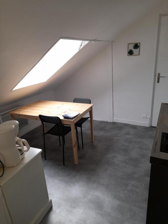 une chambre mansardée avec une table en bois et deux chaises dans l'établissement LOGEMENT VERT proche de NEOMA et de la CATHEDRALE de REIMS, à Reims