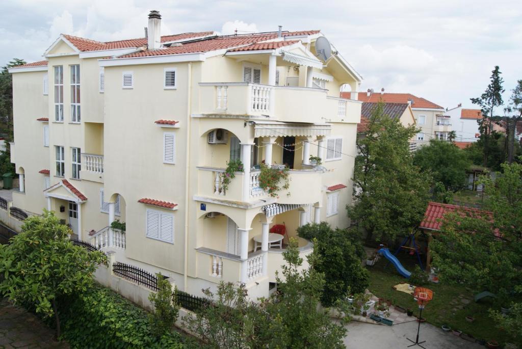 - un grand bâtiment blanc avec des balcons et des arbres dans l'établissement Apartments Marta - Zadar, à Zadar