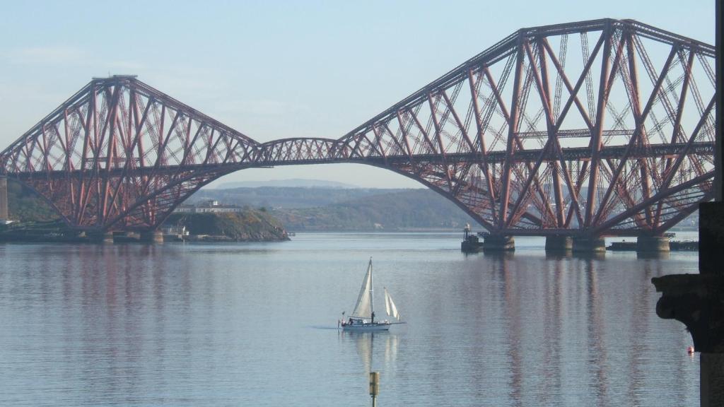 un velero en el agua bajo un puente en Crawsteps, en Queensferry