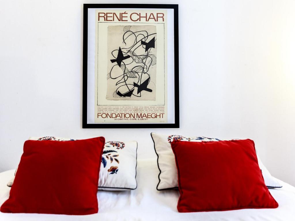 a bed with two red pillows and a framed picture at Montmartre Apartments Monet in Paris